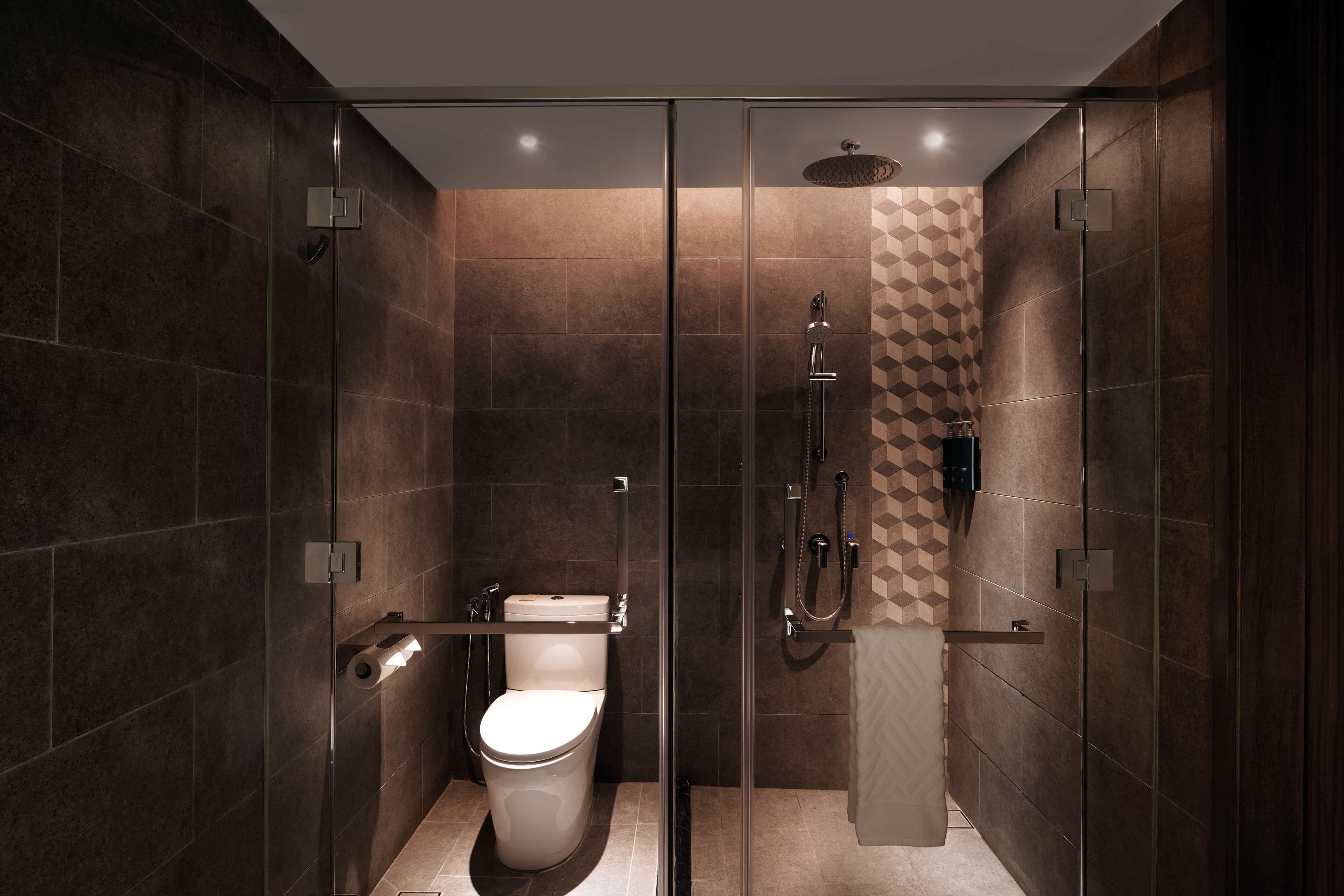 A modern bathroom with a glass-enclosed shower, a toilet, and a towel rack.