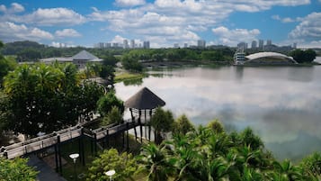 A park with a bridge, a gazebo, and a lake reflecting buildings.
