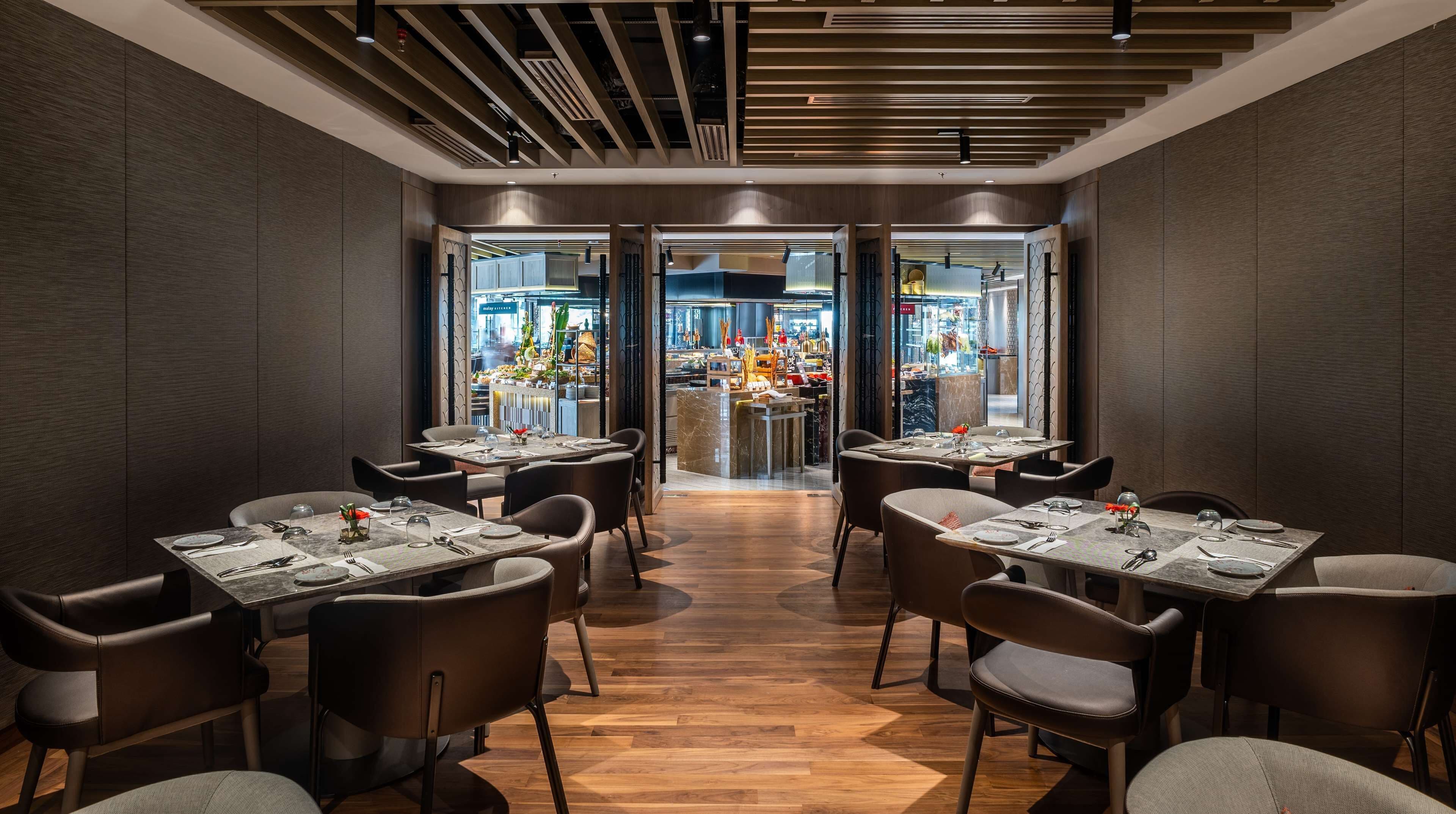 Un interior de restaurante moderno con paneles de madera oscura, una zona de bar central y un suelo de madera pulida.