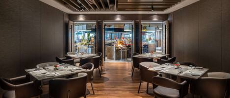 Un interior de restaurante moderno con paneles de madera oscura, una zona de bar central y un suelo de madera pulida.