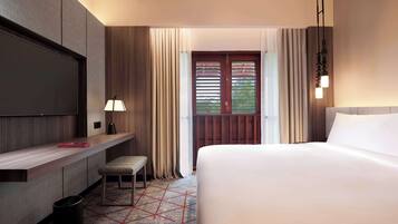 A hotel room with a large bed, a desk with a chair, a TV, and a window with curtains.
