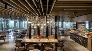 Un intérieur de restaurant moderne, avec un grand espace de restauration, un plafond haut orné de lambris en bois et un luminaire décoratif central.
