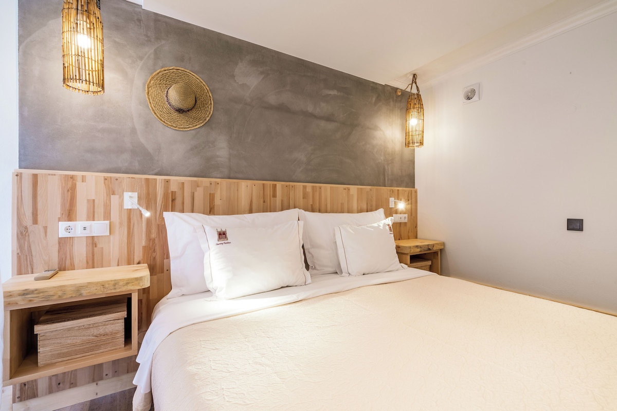 Un dormitorio con una cama grande, cabecero de madera, mesitas de noche y un sombrero colgado en la pared.