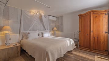 A bedroom with a bed, bedside lamps, a wardrobe, and an air conditioning unit.