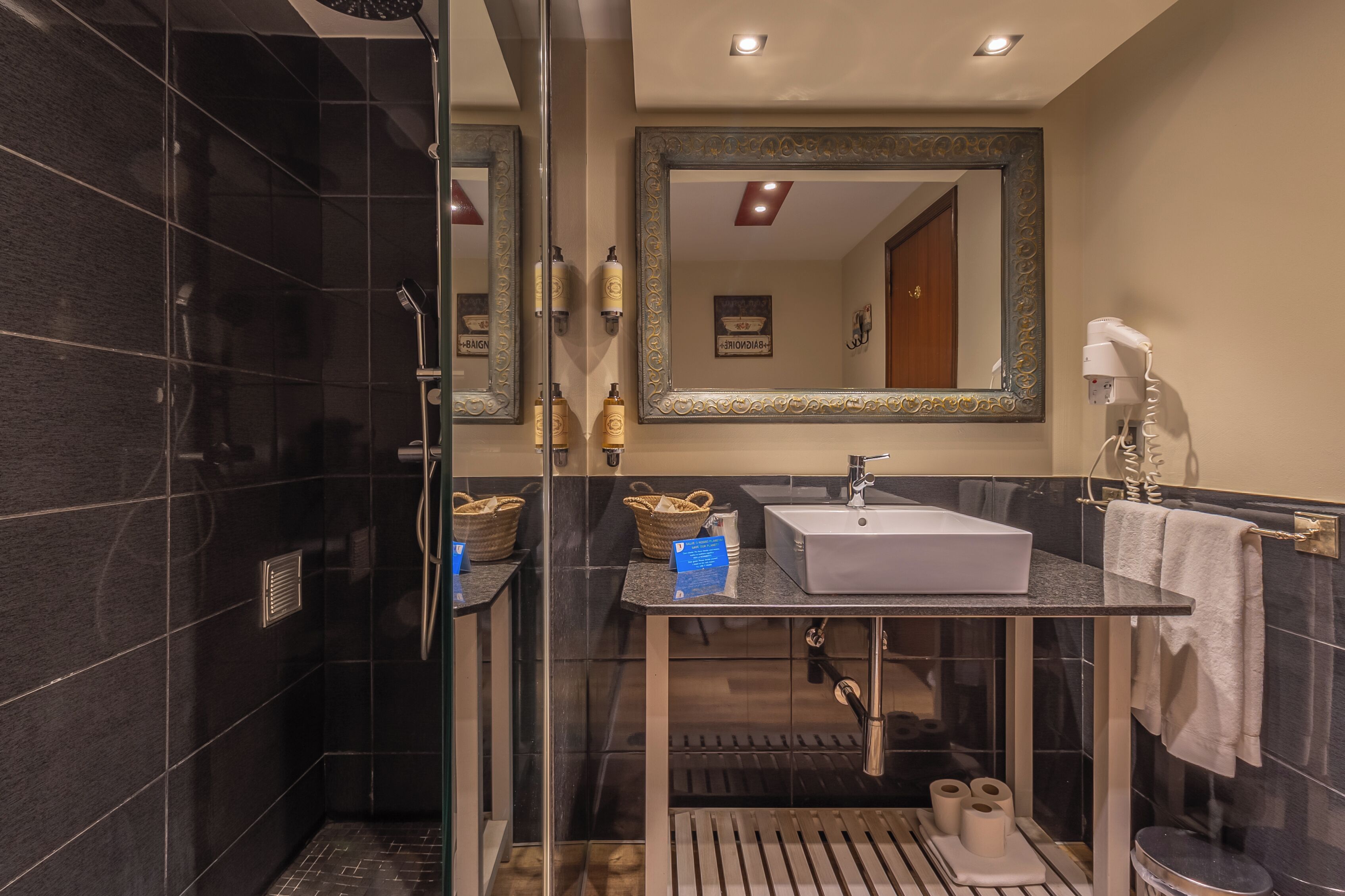 A modern bathroom with a glass shower enclosure, a vanity with a sink, and a large mirror.