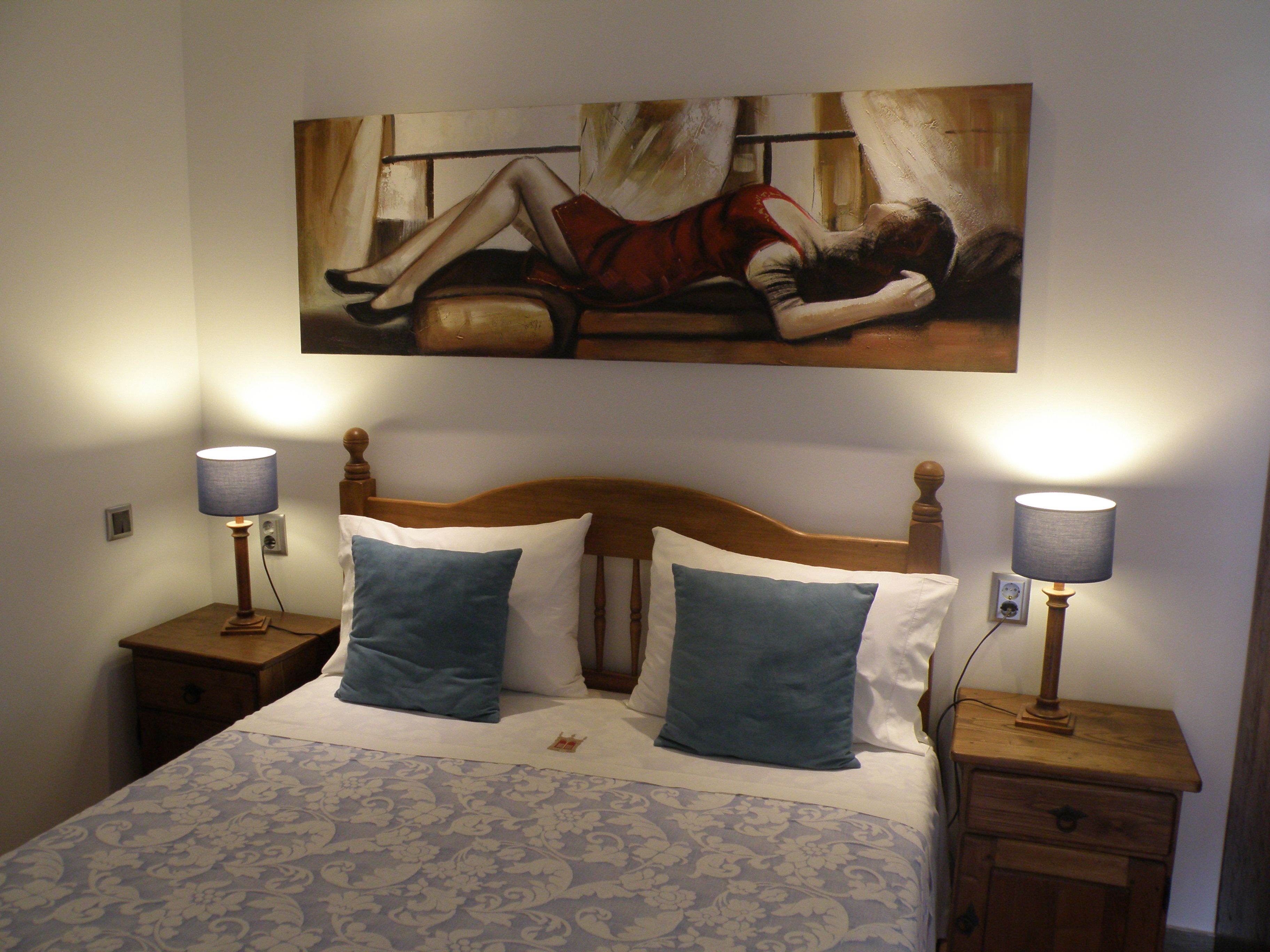 Un dormitorio con cama, dos lámparas de noche y un cuadro en la pared.
