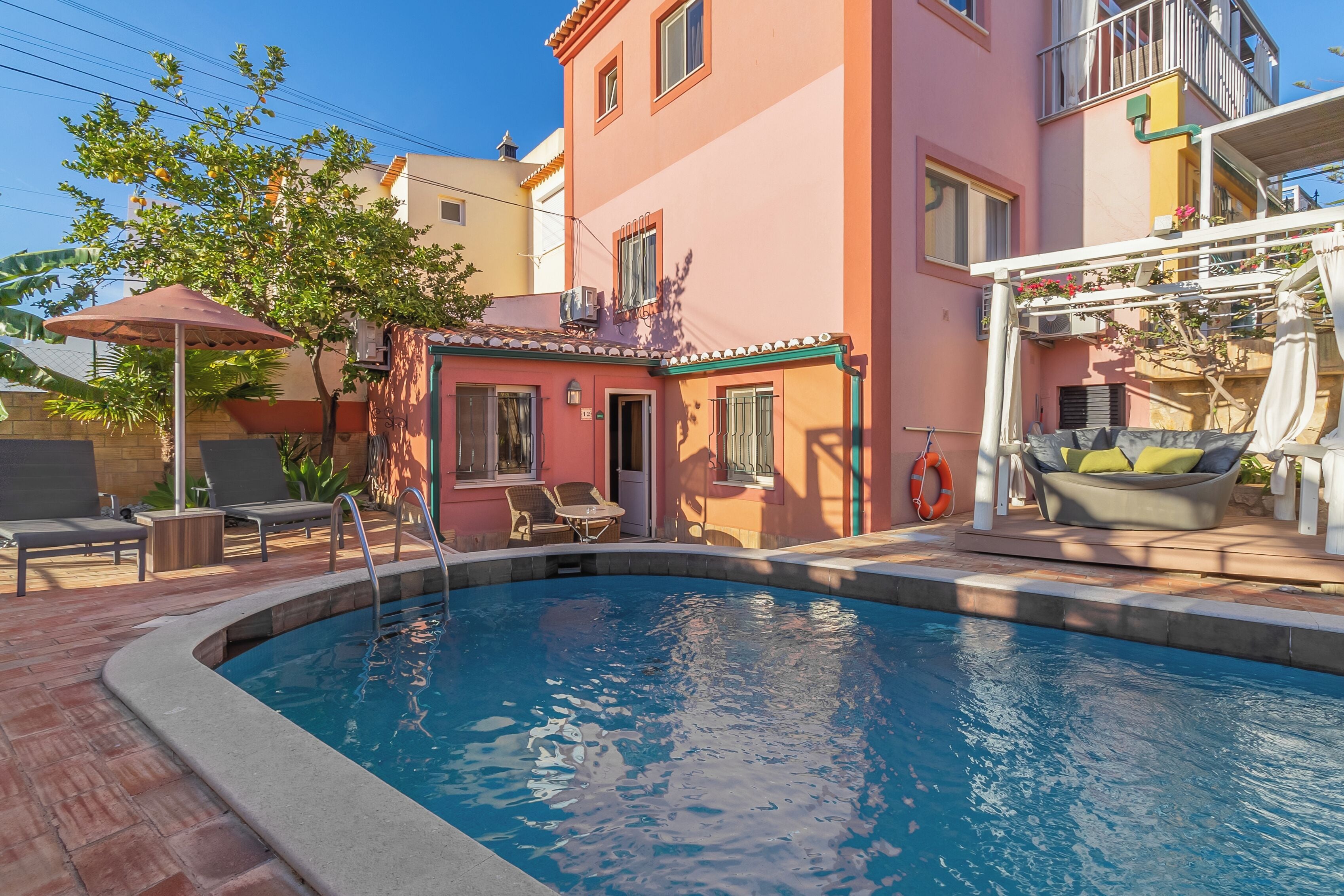 A swimming pool with lounge chairs and a small building with a door and windows.