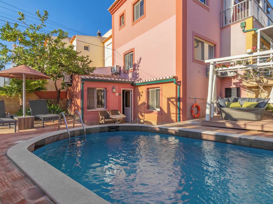 Una piscina con sillas de descanso y un pequeño edificio con puerta y ventanas.