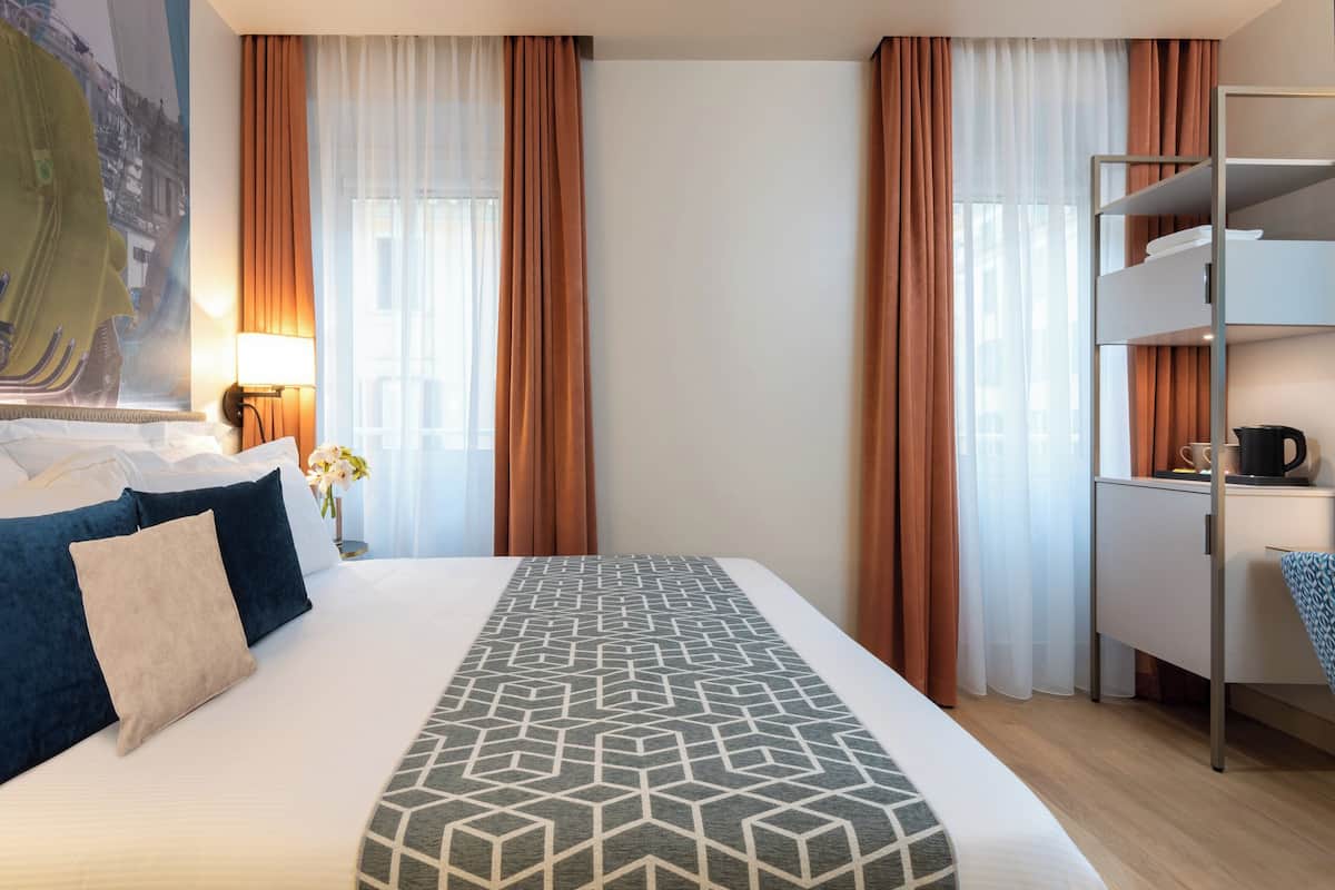 Habitació d'hotel amb un llit, un escriptori i una lliterà.