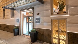 A hotel entrance with a glass door, a sign for 'Leonardo Boutique', and two potted plants. - Leonardo Boutique Hotel Rome Termini (Rome)