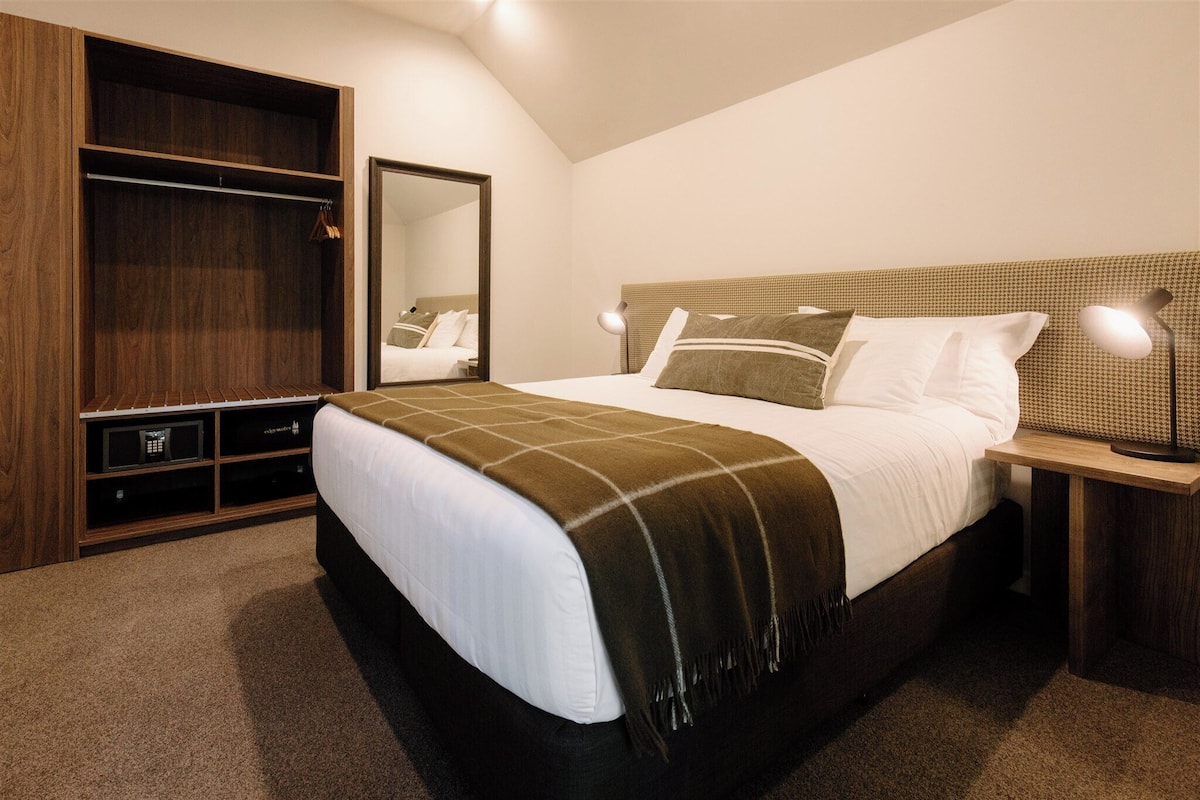 Ein Schlafzimmer mit einem großen Bett, einem Kleiderschrank, einem Spiegel und Nachttischlampen.