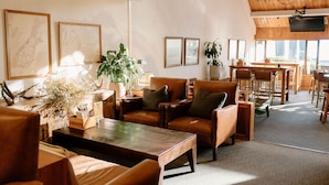 A spacious living area with leather sofas, a wooden coffee table, and framed artwork on the walls. - Edgewater (Wanaka)