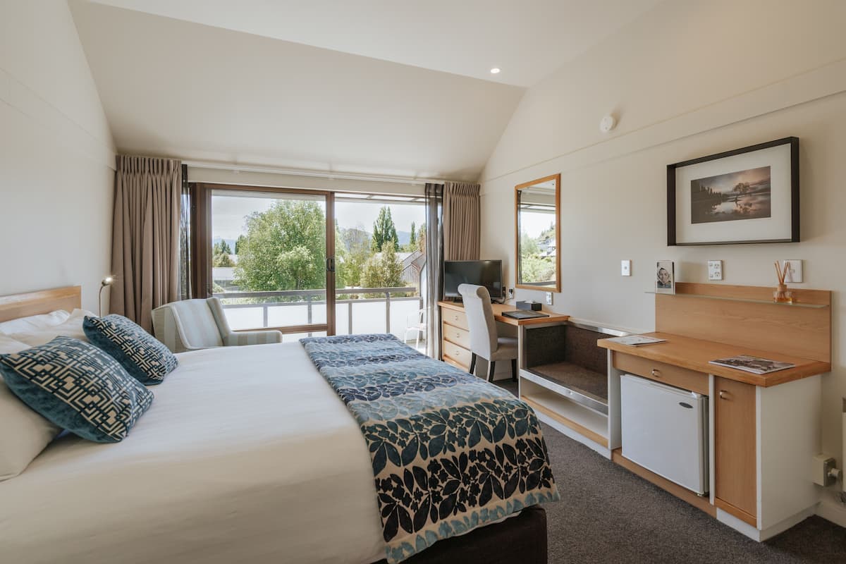 Ein Hotelzimmer mit Bett, Schreibtisch, Stuhl und einem kleinen Kühlschrank.