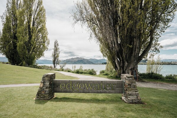 A wooden bench with 'edgewater' engraved on it, surrounded by trees and a lake view.