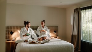 A hotel room with a large bed, a bedside table with a lamp, and a window with curtains. - Edgewater (Wanaka)