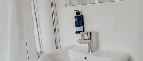 A modern bathroom with a white sink, a mirror, and a shower curtain.