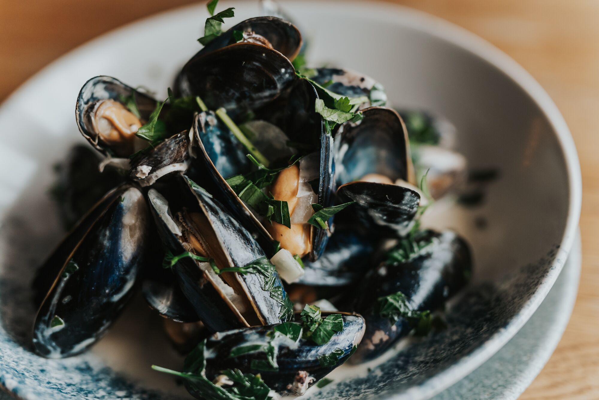 Un plato de mejillones con vegetales de hoja verde y hierbas.