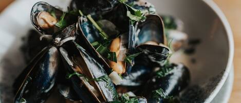 Un plato de mejillones con vegetales de hoja verde y hierbas.