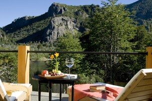 A balcony with a table set for a meal, overlooking a mountainous landscape.