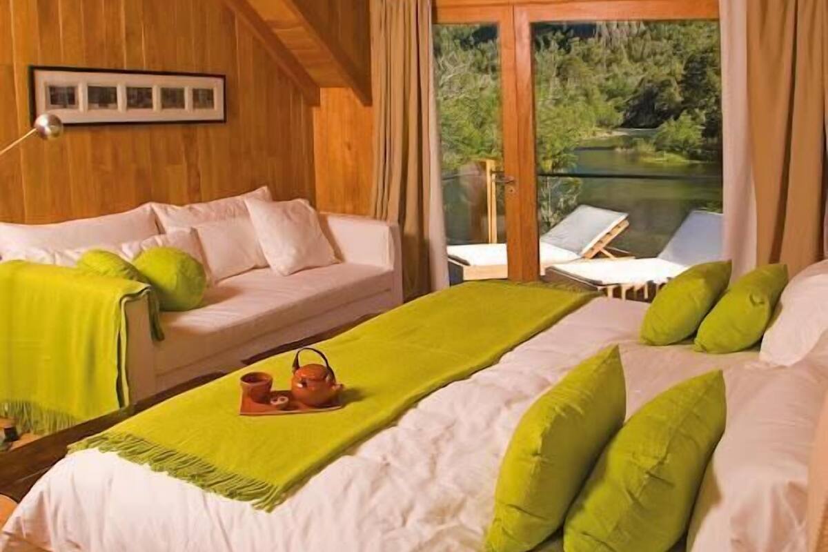 A cozy room with a bed, a sofa, and a view of a lake.