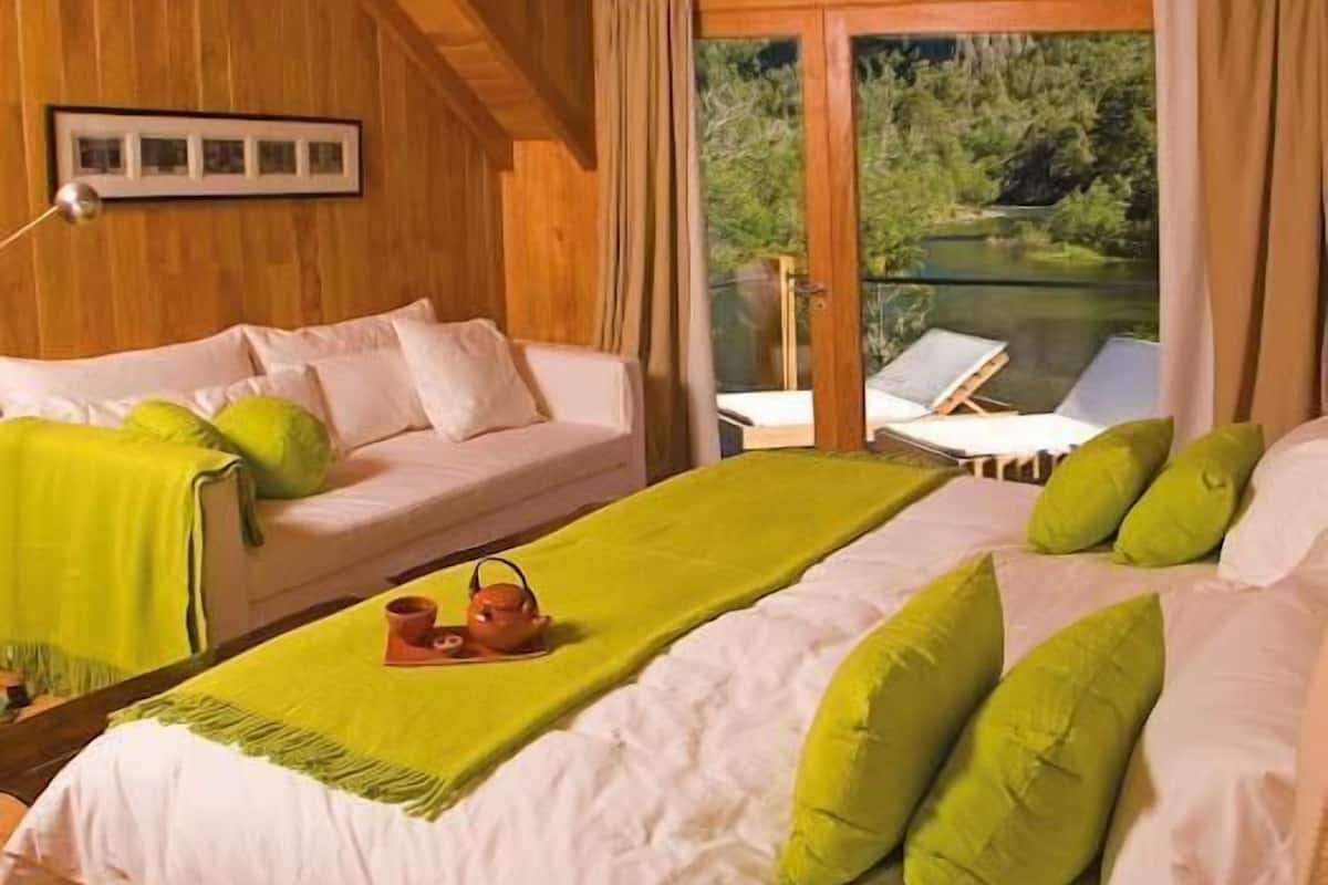 A cozy room with a bed, a sofa, and a view of a lake.