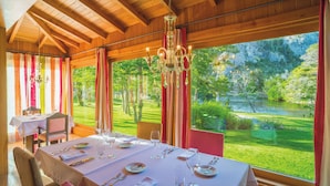 A dining area with a table set for four, large windows, and a chandelier. - Rio Hermoso Hotel De Montaña (San Martín de los Andes)