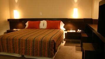 Una habitación de hotel con una cama grande, dos lámparas de noche, un escritorio y una silla.