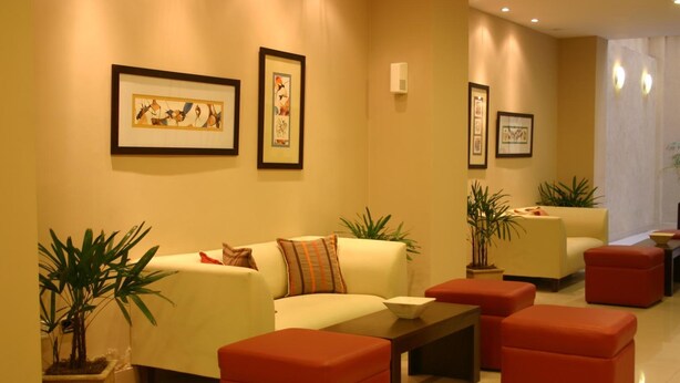 A modern lounge area with a sofa, red ottomans, and framed artwork on the walls. - Cordon del Plata (Mendoza)