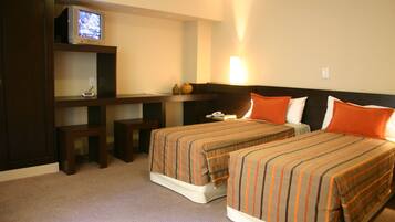 A hotel room with two beds, a desk, a television, and a nightstand.