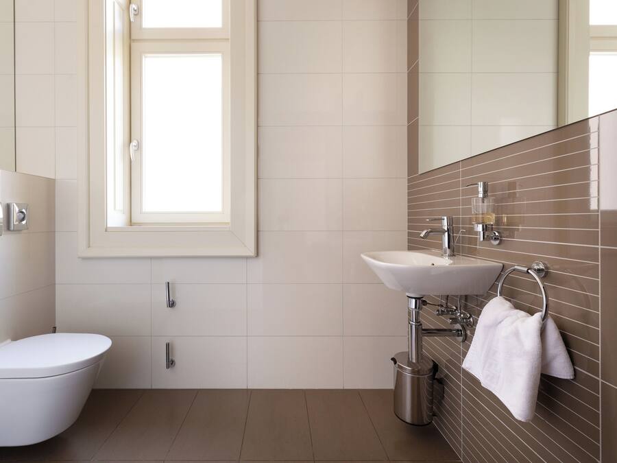 Ein modernes Badezimmer mit Toilette, Waschbecken und Spiegel.