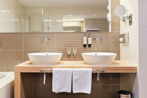 A modern bathroom with two sinks, a glass shower enclosure, and a large mirror.