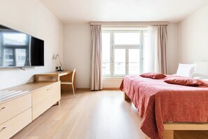 A bedroom with a bed, a desk, and a TV.