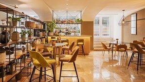 A modern bar area with a variety of bottles and glasses, wooden shelves, and comfortable seating. - Hotel Vincci Baixa (Lisbon)