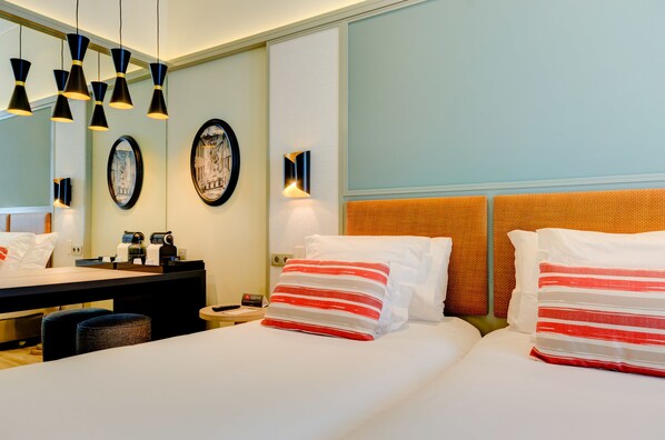 Quarto de hotel com cama, mesas de cabeceira, escrivaninha e um espelho grande.