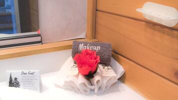 A bathroom with a window, a towel rack with a red flower, and a sign offering towel drying options.