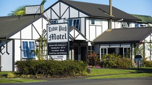 Tudor Park Motel with a signboard listing amenities like spacious units, swimming pool, SKY TV, free internet, movies, ground floor with full kitchens, and vacancies. - Tudor Park Motel (Gisborne)