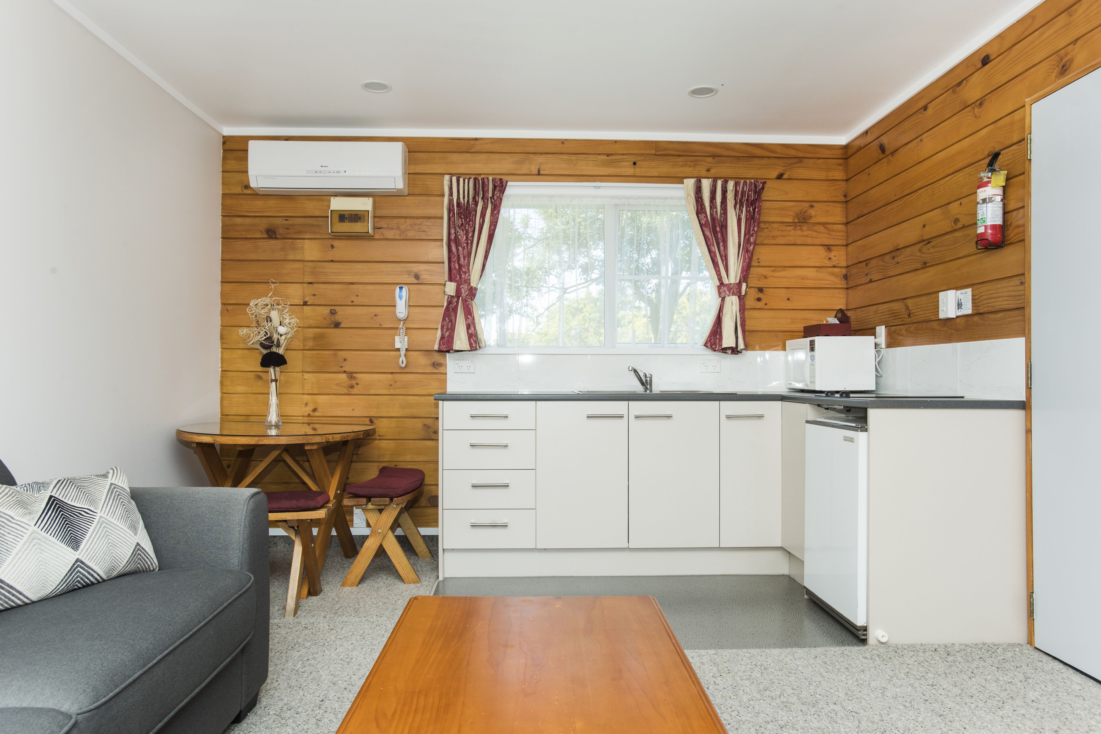 A compact kitchen with wooden paneling, a white refrigerator, a sink, and a dining area with a table and chairs.