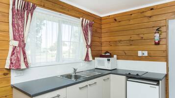 Una cocina funcional con paredes de madera, un lavamanos, un microondas y un lavavajillas.