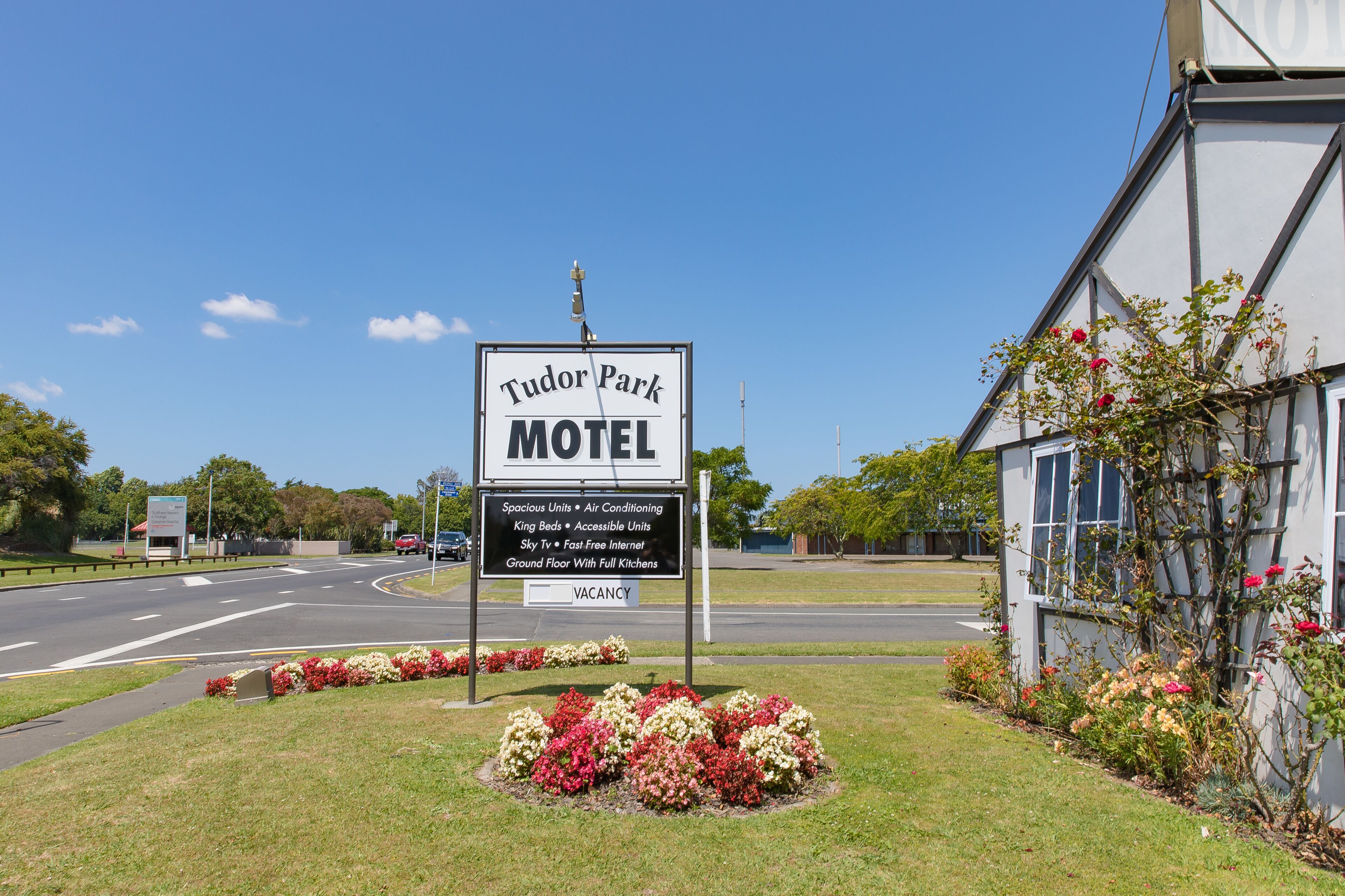 A Tudor Park Motel sign with a list of amenities including spacious units, air conditioning, king beds, accessible units, sky view, free internet, and a ground floor with full kitchens.