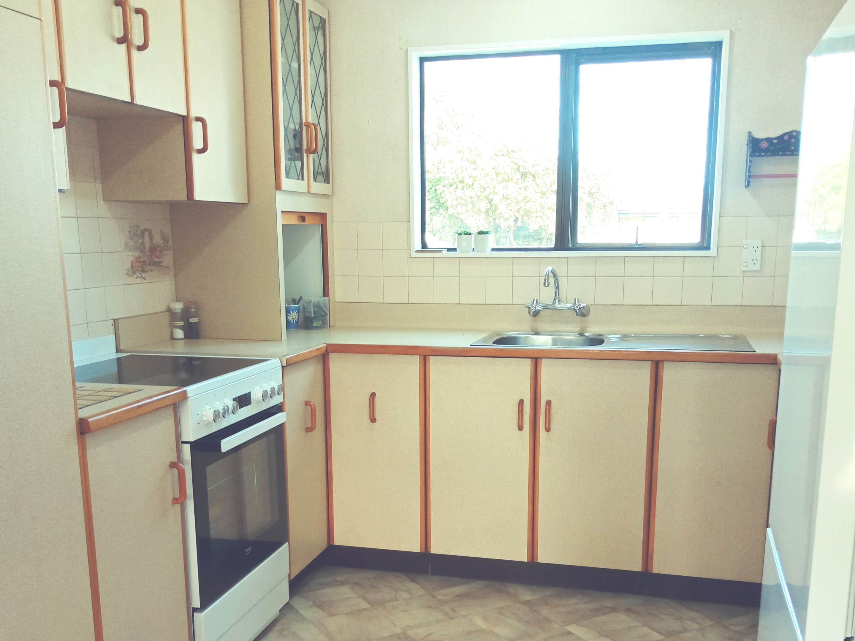 A kitchen with a stove, oven, sink, and window.