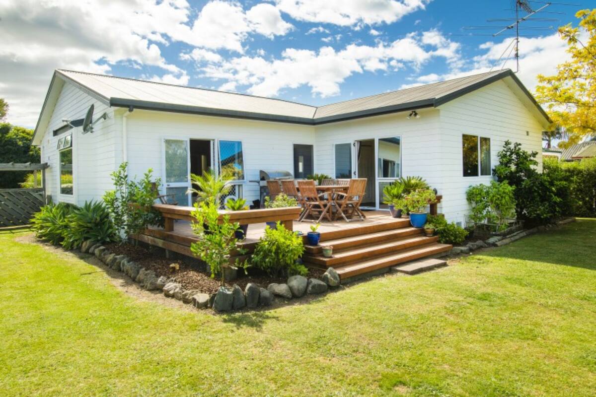 A single-story house with a patio, outdoor furniture, and a barbecue grill.