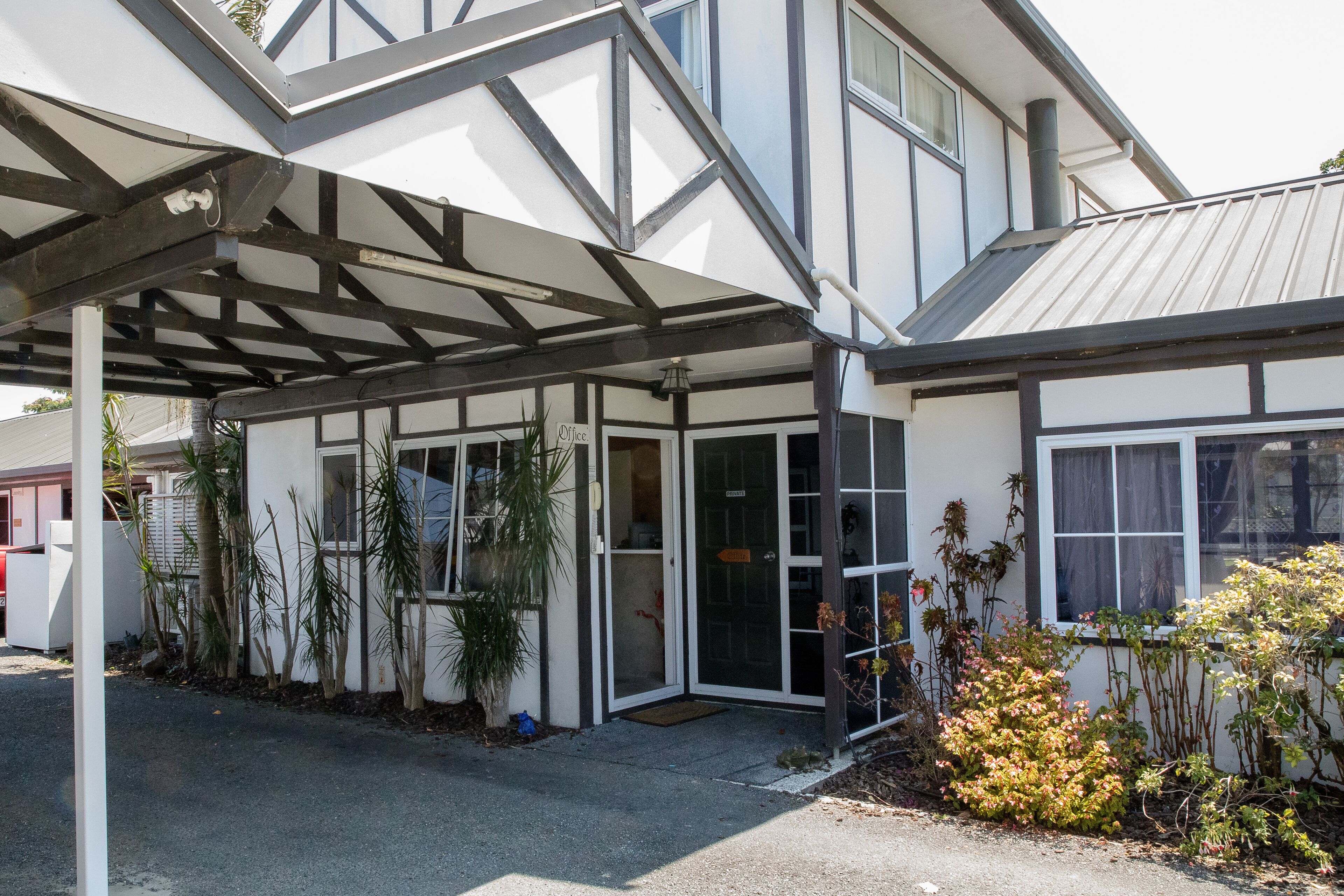 A modern building with a covered entrance, large windows, and a well-maintained garden area.