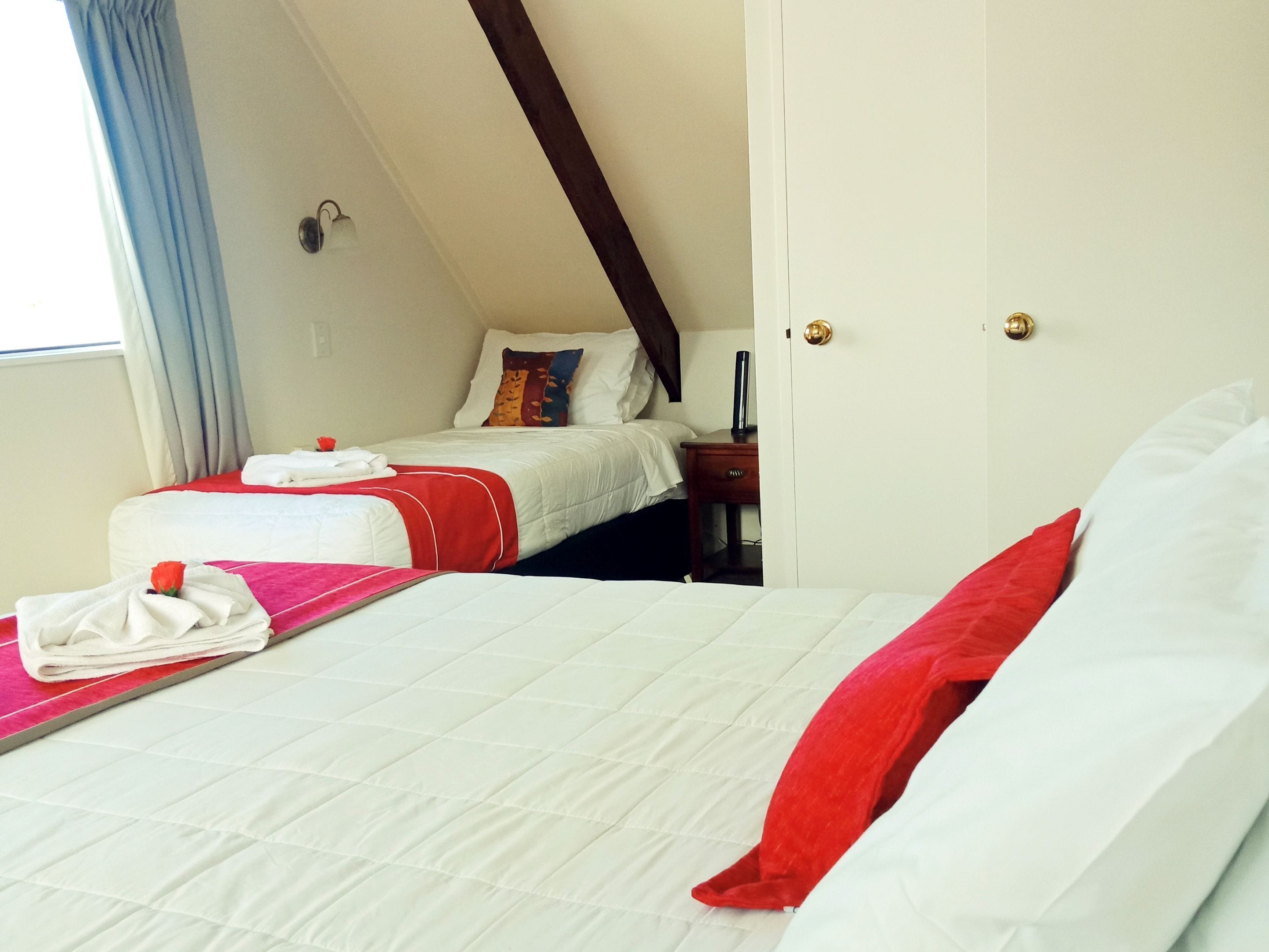 A hotel room with a bed, a bedside table, and a window with curtains.
