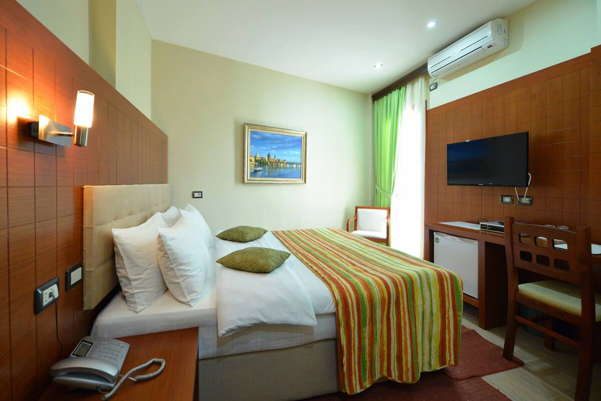 Une chambre d’hôtel équipée d’un lit, d’un bureau, d’une chaise, d’une télévision et d’un appareil de climatisation.