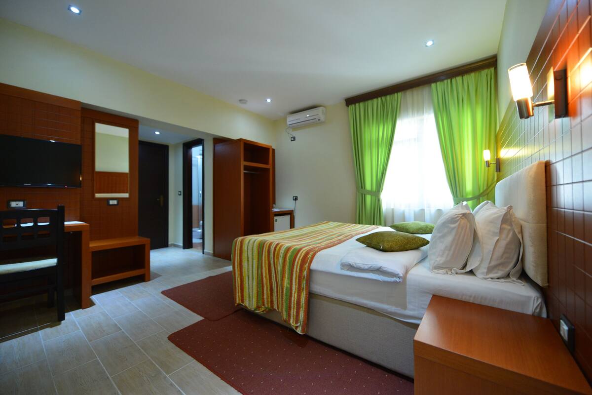 Une chambre d’hôtel équipée d’un lit, d’un bureau, d’une télévision et d’une armoire.