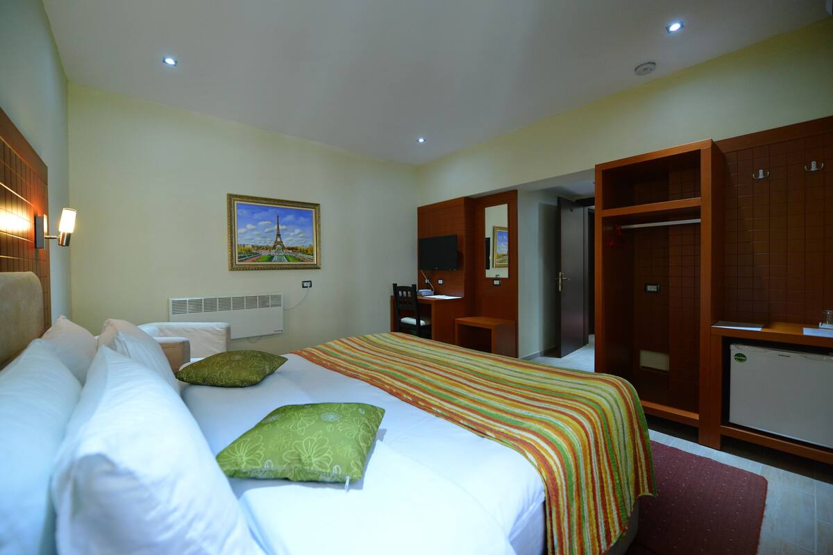 Une chambre d’hôtel comprenant un lit, un bureau, une chaise, une armoire et un téléviseur.