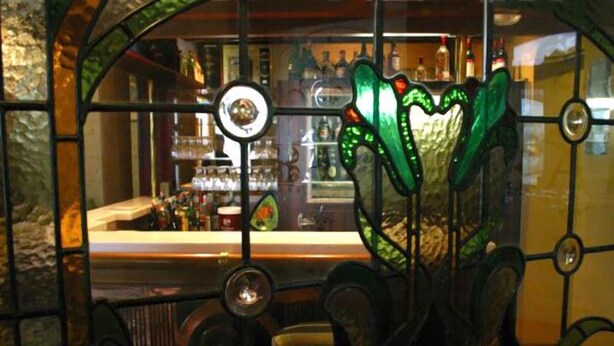 A bar with a green glass partition and a circular mirror. - Victoria Railway Hotel (Invercargill)
