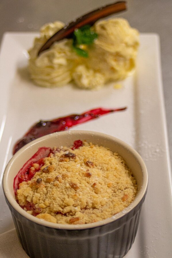 A dessert dish with a crumbly topping and a berry compote, served on a white plate.