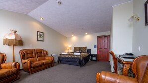 A hotel room with a bed, two leather sofas, a desk, and a lamp. - Victoria Railway Hotel (Invercargill)