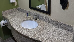 A bathroom with a granite countertop, a white sink, a mirror, and two wall-mounted towel racks. - Sleep Inn & Suites at Six Flags (San Antonio)
